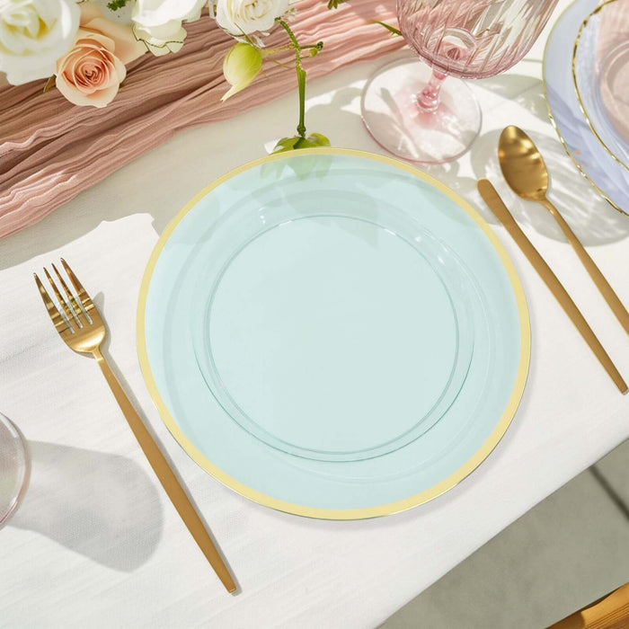 Aqua plate with gold rim set on a table with elegant cutlery and floral decor.