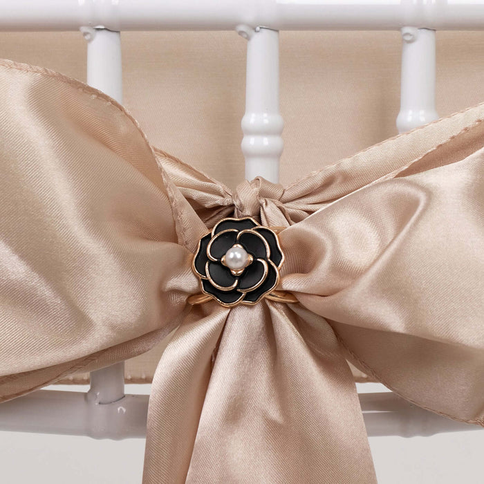 Elegant satin bow with black flower accent and pearl detail on a chair.