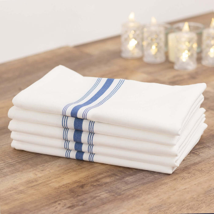Stack of white kitchen towels with blue stripes on a wooden surface.