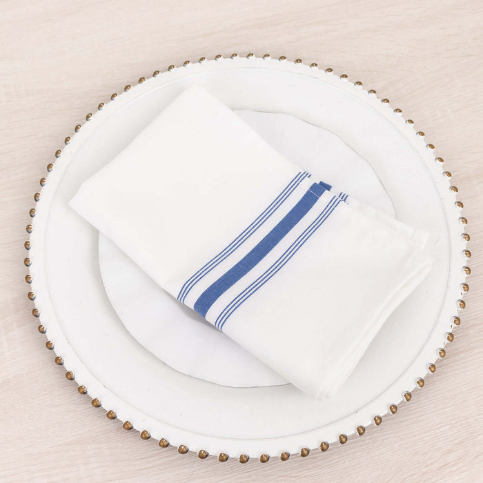 White napkin with blue stripes on a decorative plate.