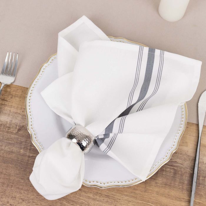 White napkin with silver holder elegantly arranged on a decorative plate.