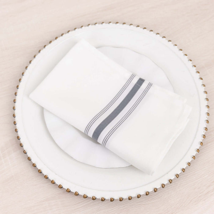 White napkin with gray stripes on a decorative plate.