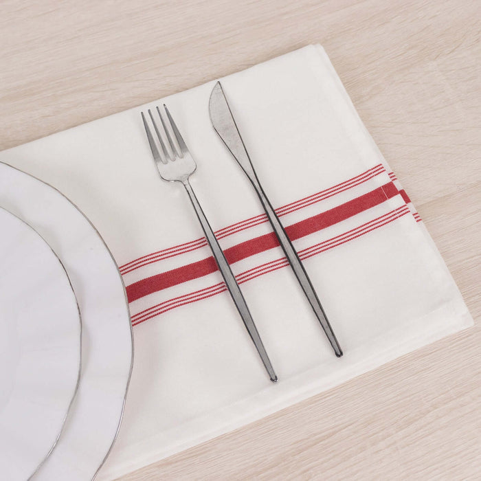 Elegant table setting with white plates, fork, and knife on a red-striped napkin.