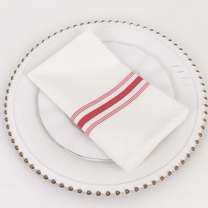 White napkin with red stripes on a decorative plate.