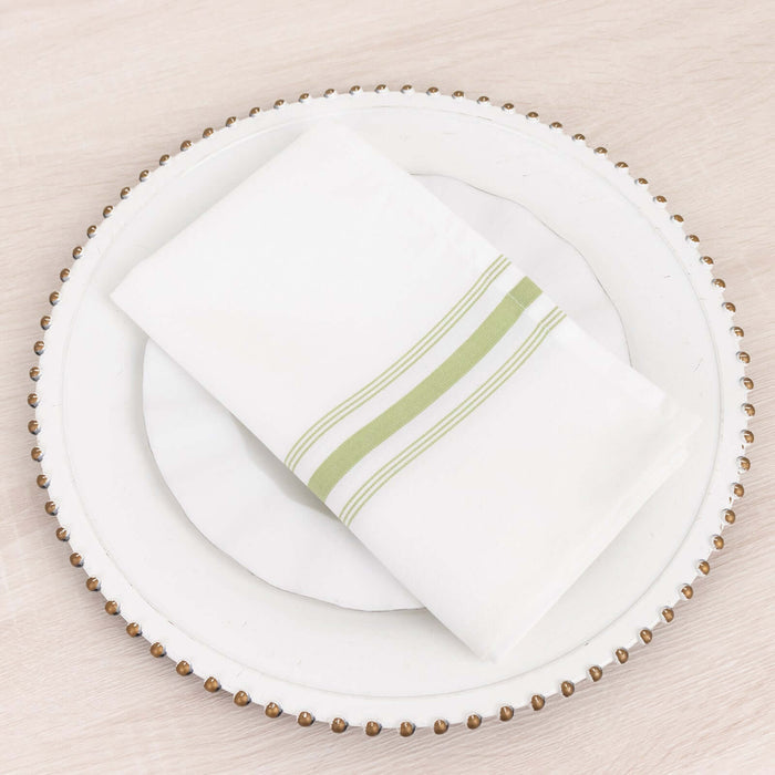 White napkin with green stripes on a decorative plate.
