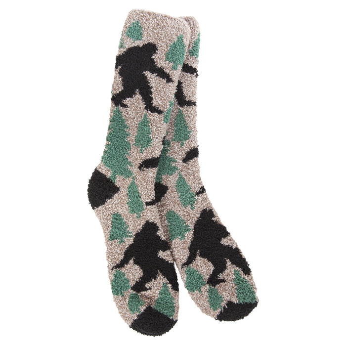A pair of plush, fuzzy 1902 crew socks featuring a camouflage pattern of green pine trees and black Bigfoot silhouettes on a light beige background.