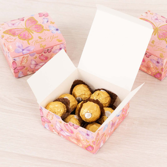 Open gift box with chocolate truffles inside, adorned with butterfly design.