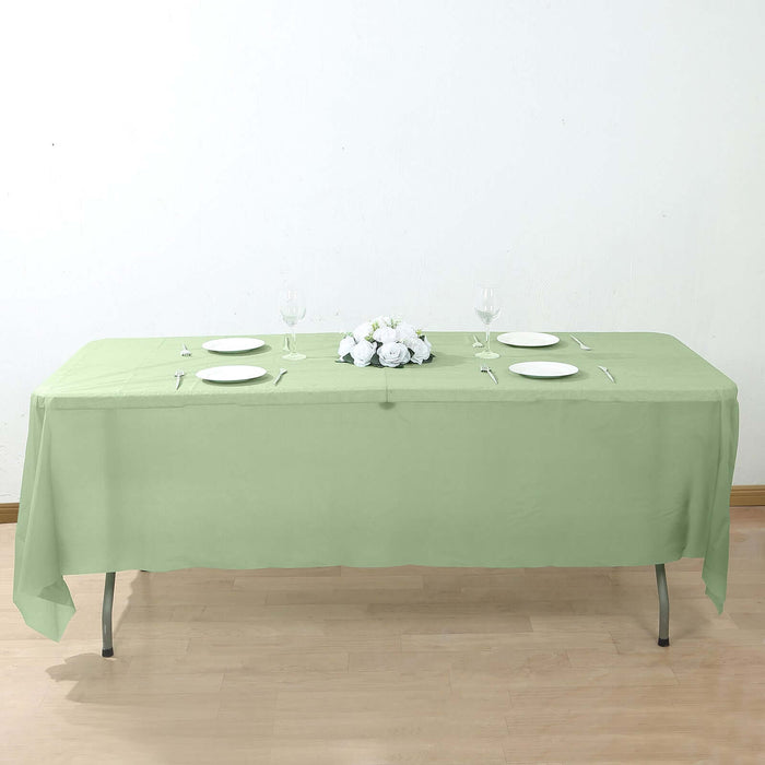 Green tablecloth draped over a table set with plates and a floral centerpiece.
