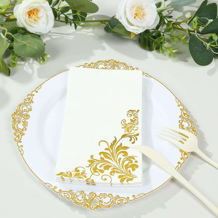 Elegant white napkin with gold floral design on decorative plate with utensils.