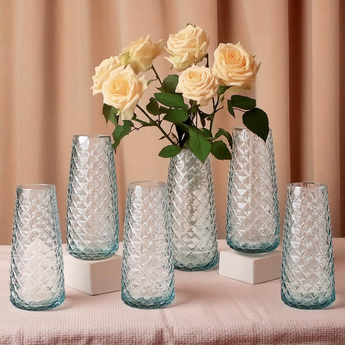 Elegant glass vases with roses, arranged on a soft fabric backdrop.