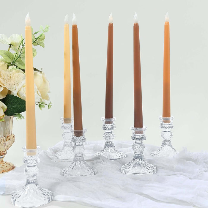 Elegant tapered candles in crystal holders with floral arrangement.
