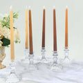 Elegant tapered candles in crystal holders with floral arrangement.