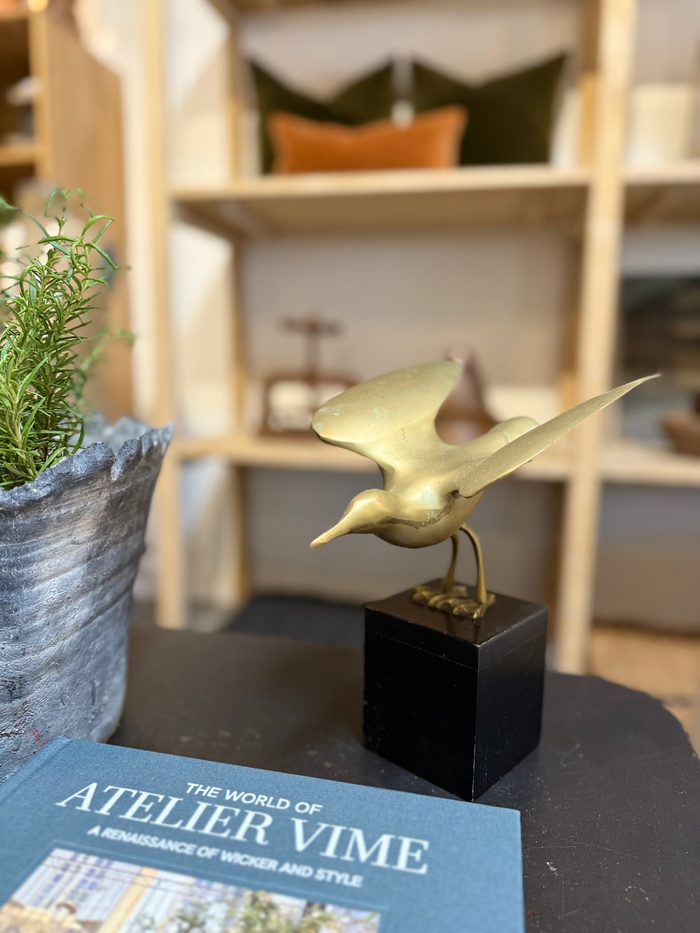 Brass sparrow ornament on dark stand, side view