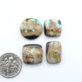 Black Jack turquoise cabochons, blue-green color with black matrix, polished stones on a white background with a US dime for scale