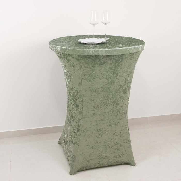 Green velvet cocktail table with two glasses and a plate on top.