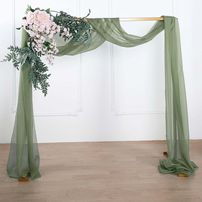 Wedding arch with greenery and pink flowers, draped in sheer fabric.