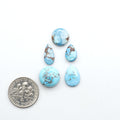 Golden Hills Turquoise cabochons, icy blue to lavender tones with chocolate matrix, polished stones on a white background with a US dime for scale