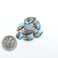 Golden Hills Turquoise cabochons, icy blue to lavender tones with chocolate matrix, polished stones on a white background with a US dime for scale