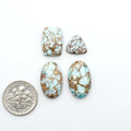 Golden Hills Turquoise cabochons, icy blue to lavender tones with chocolate matrix, polished stones on a white background with a US dime for scale