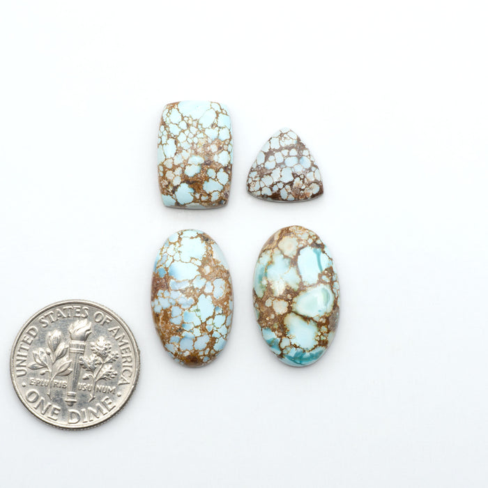 Golden Hills Turquoise cabochons, icy blue to lavender tones with chocolate matrix, polished stones on a white background with a US dime for scale