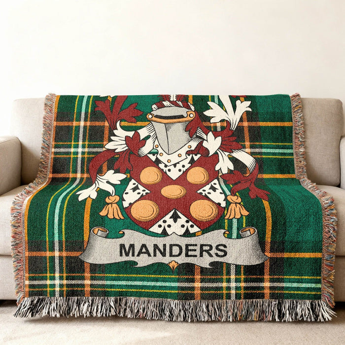 Green tartan blanket with Manders crest draped on a sofa.