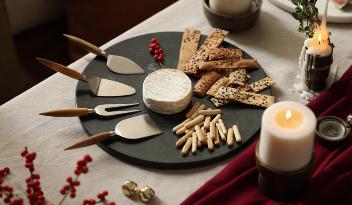 Round dark green marble serving platter with smooth surface, styled with snacks and candle