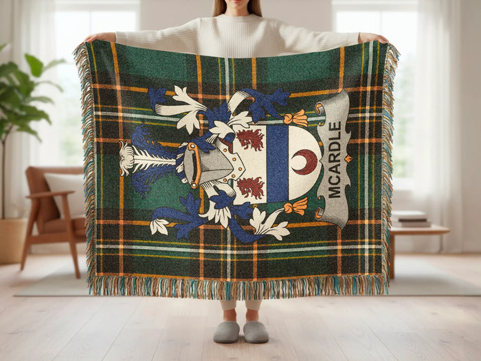 Tartan throw blanket with Mcardle crest held up by a person.