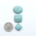 Number 8 turquoise cabochons, classic color with distinctive matrix, polished stones on white background with US dime for scale