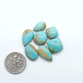Pilot Mountain Turquoise cabochons, blue-green gemstones with natural matrix on a white background with a US dime for scale