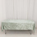 Green textured tablecloth draped over a table on a plain backdrop.