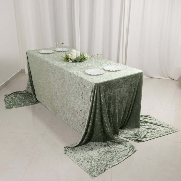 Green velvet tablecloth draped over a table with plates and candles.