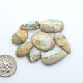 Royston Turquoise cabochons, blue-green color with natural matrix, polished stones on a white background, with a US dime for scale