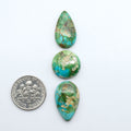 Sonoran Mountain Turquoise cabochons, blue-green color with natural matrix, polished stones on a white background, with a US dime for scale
