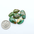 Sonoran Mountain Turquoise cabochons, blue-green color with natural matrix, polished stones on a white background, with a US dime for scale