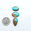 Sonoran Mountain Turquoise cabochons, blue-green color with natural matrix, polished stones on a white background, with a US dime for scale
