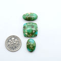 Sonoran Mountain Turquoise cabochons, blue-green color with natural matrix, polished stones on a white background, with a US dime for scale