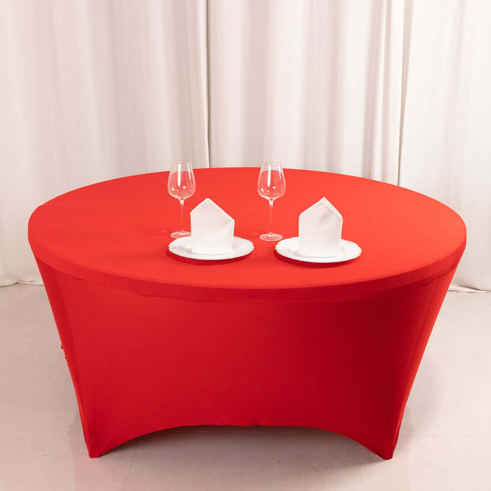 Round red table with white plates and glasses, elegantly set for dining.