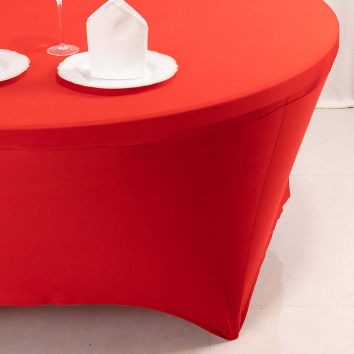 Red tablecloth draped over a round table with white plates and napkins.