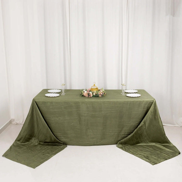 Elegant olive green tablecloth draped over a table with floral centerpiece and plates.