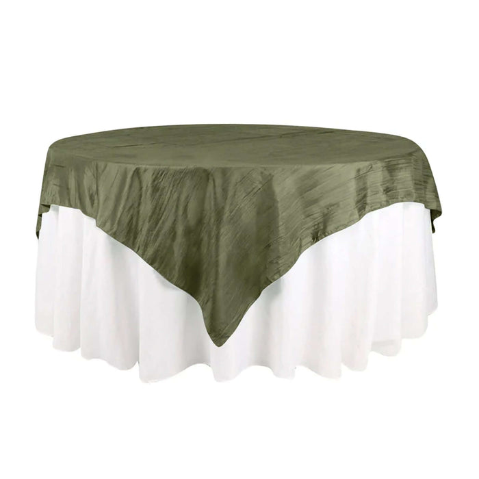 Olive green tablecloth draped over a round table with white skirt