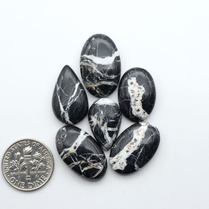 Black and white marbled stones with a quarter for scale on a white background.