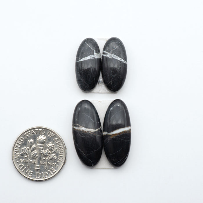White Buffalo stone cabochons, white stone with black matrix, polished stones on a white background, with a US dime for scale