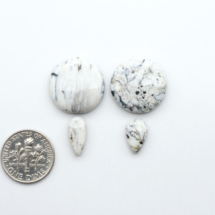 White marbled stones with a dime for scale on a white background.Natural White Buffalo Stone Cabochons are semi-precious gemstones cut into shapes ideal for jewelry-making, making them an excellent choice for artisans.