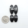 White Buffalo stone cabochons, white stone with black matrix, polished stones on a white background, with a US dime for scale